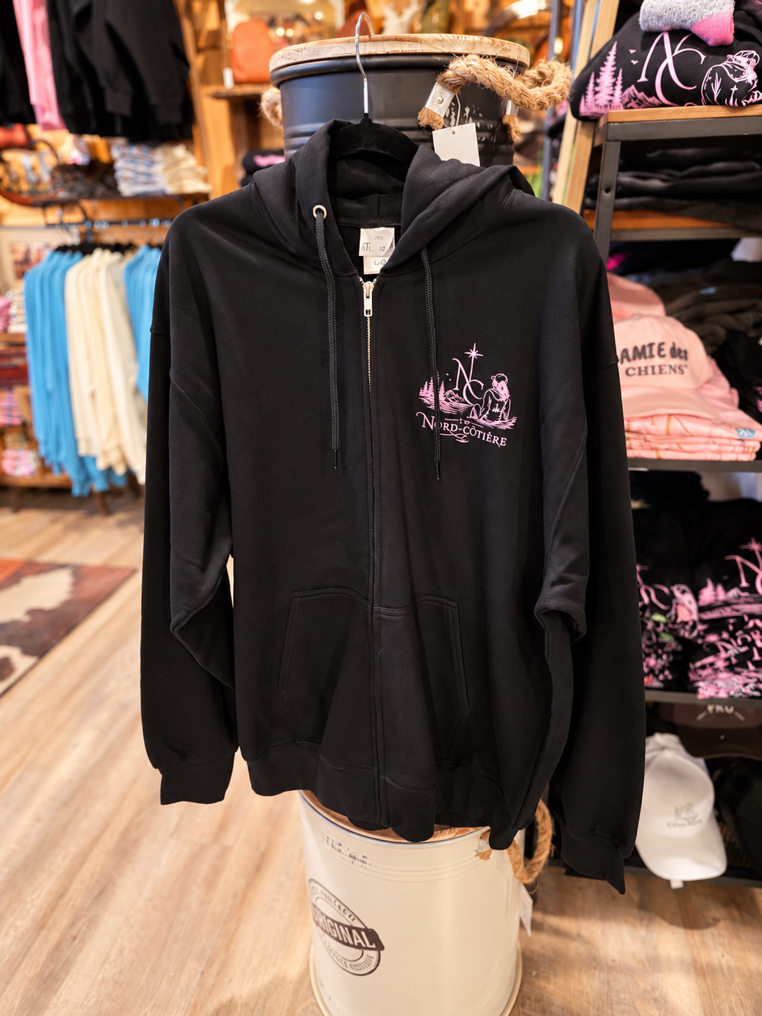 Veste noire à capuchon et fermeture à zip La Nord-Côtière avec broderie rose sur la poitrine.