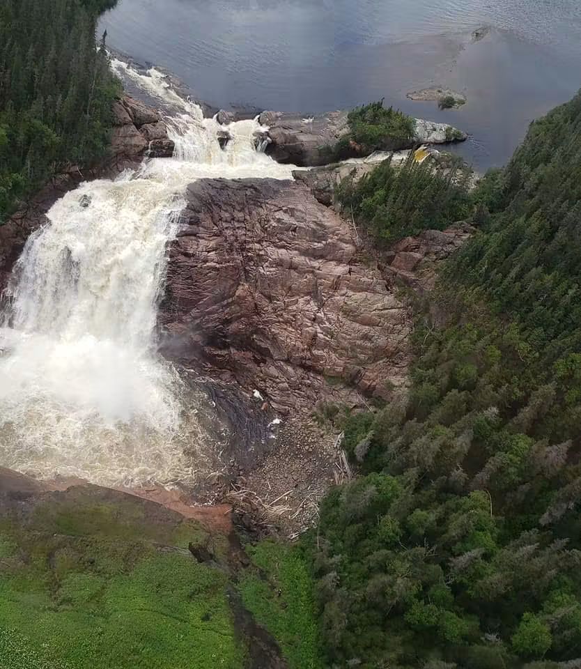 Vue plongeante d’une chute d’eau entre des parois rocheuses bordées de forêt.