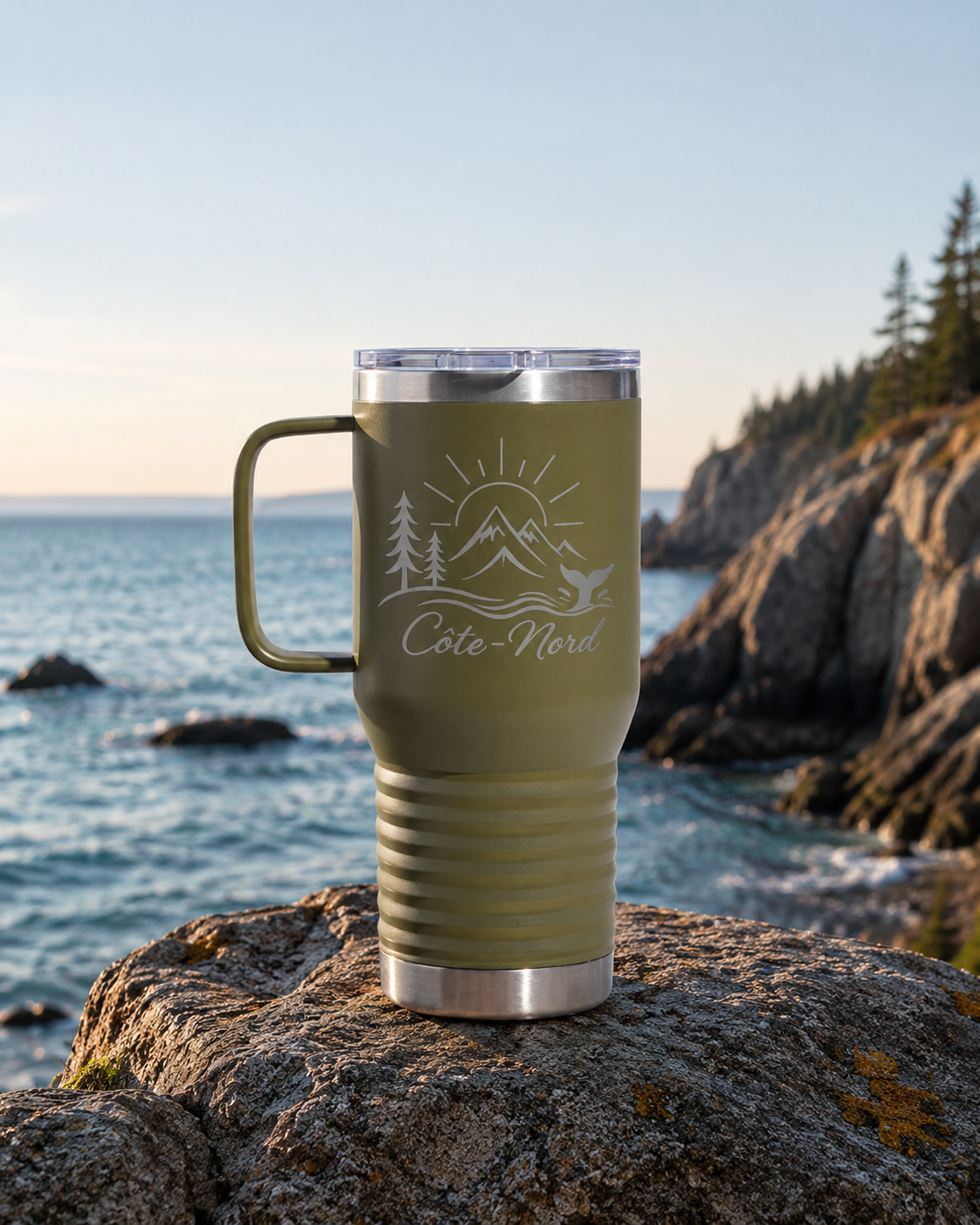 Tasse thermos Côte-Nord couleur vert olive avec gravure laser, posée sur un rocher au bord de la mer